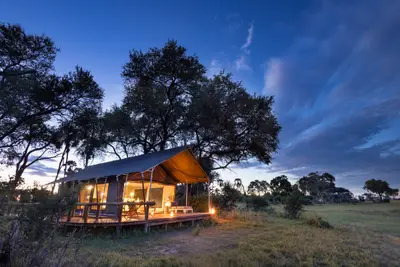 Raised luxury tent lit up at dusk