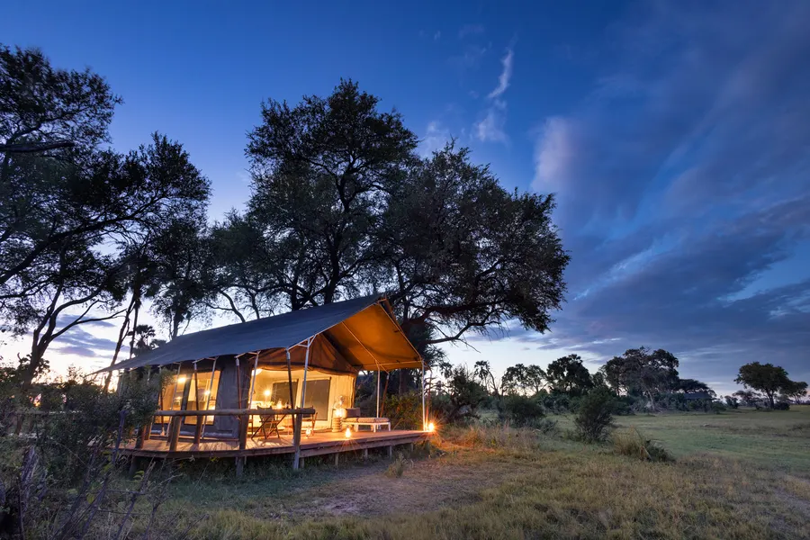 Raised luxury tent lit up at dusk