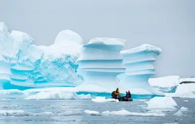 Zodiac among sculpted blue icebergs