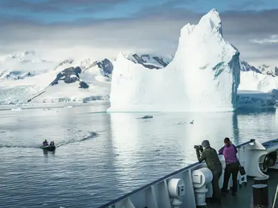 Guests on deck watching a towering iceberg