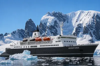 Terra Nova Adventurer among icebergs below Antarctic peaks