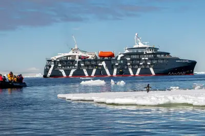 Magellan Explorer beside sea ice with a Zodiac returning