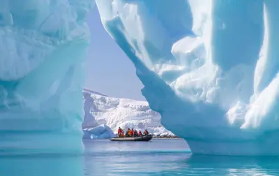 Zodiac cruising beneath an iceberg arch