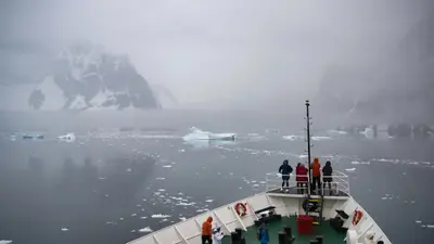 Guests on the bow in misty Antarctic waters