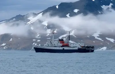 MV Ushuaia below clouded Antarctic peaks