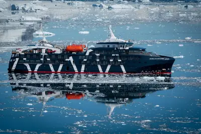 Magellan Explorer reflected in still, ice-strewn water